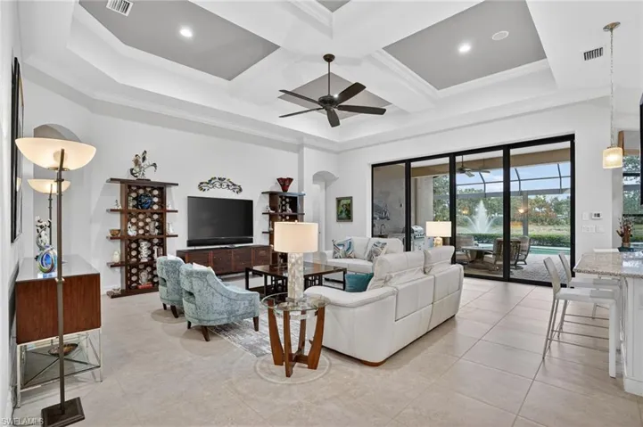 Large and open family room featuring tray ceiling with crown moulding, recessed lighting, and ceiling fan