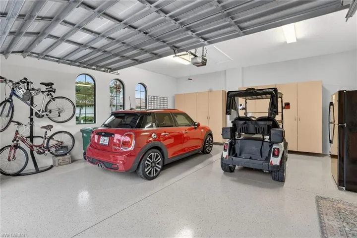 Featuring included golf cart w/lithium battery, custom storage cabinets, newer refrigerator, and epoxy flooring