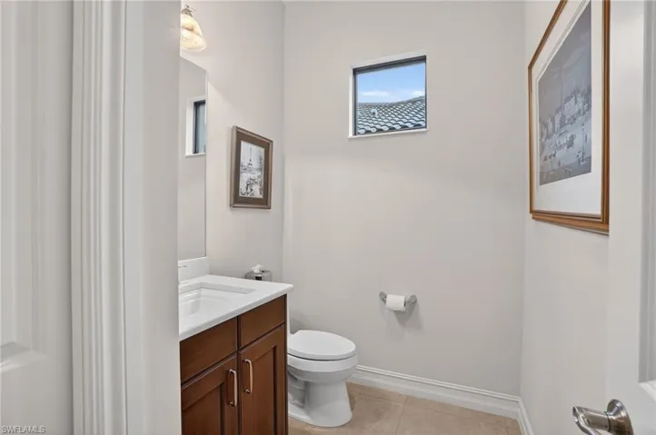 Powder room featuring vanity, adult height toilet, and light tiled porcelain floors