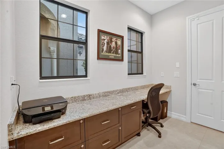 Currently used an office and work area located in hallway leading to the 2-car attached garage, porcelain tiled floors, chair and printer are included.