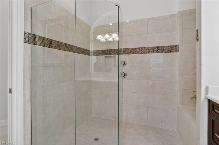 Primary shower with frameless glass doors with tiled shower and vanity
