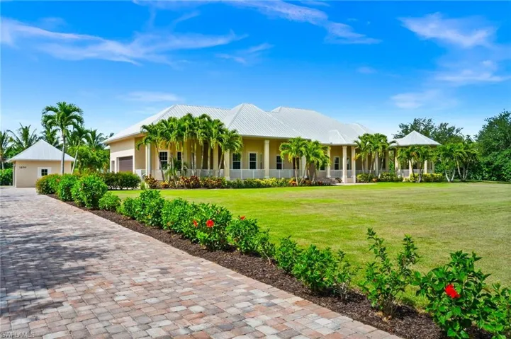 View of front of house featuring a front lawn, covered porch, metal roof, and stucco siding