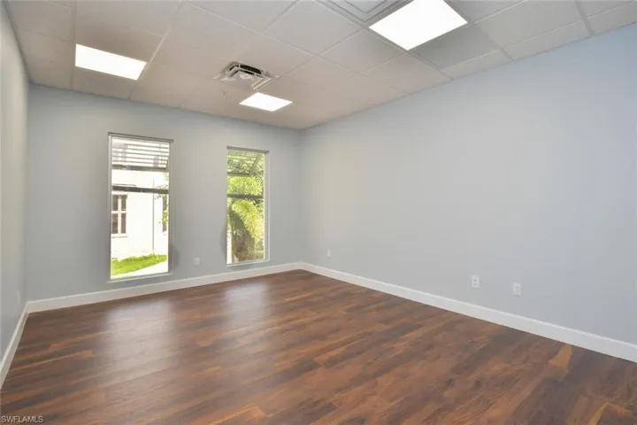 Unfurnished room with a drop ceiling and dark hardwood / wood-style floors