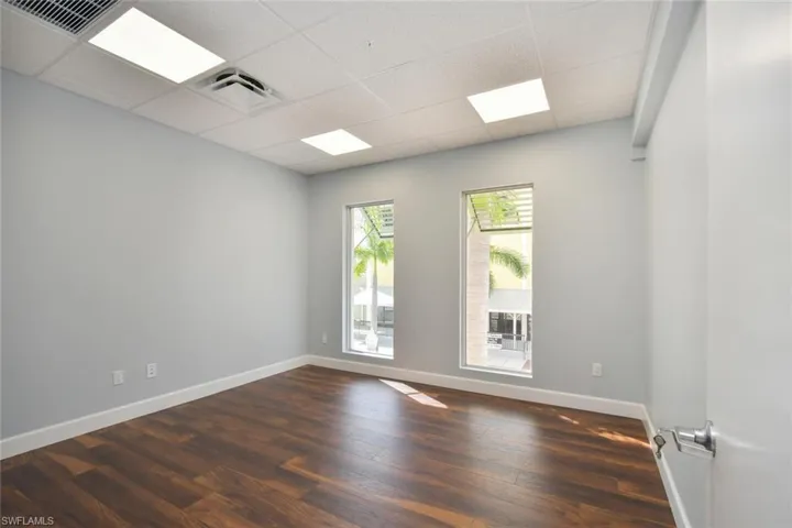 Empty room featuring dark wood-type flooring and a drop ceiling