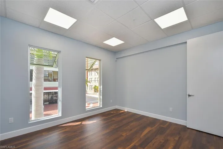 Unfurnished room featuring dark hardwood / wood-style floors and a paneled ceiling