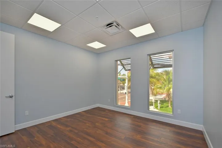 Empty room with a drop ceiling and dark hardwood / wood-style flooring