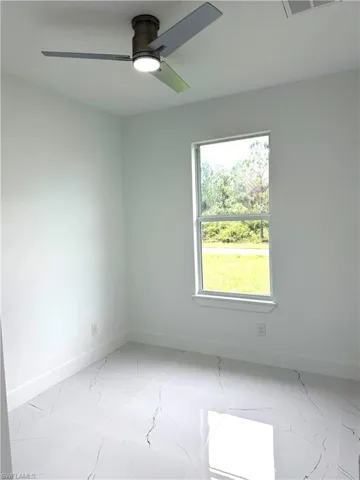 Spare room with light marble finish floors and ceiling fan