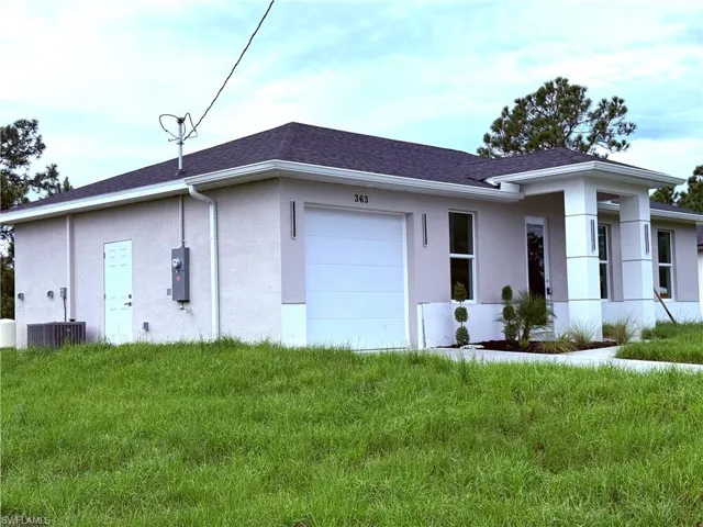 View of front of home featuring stucco siding, a shingled roof, a garage, and a front lawn