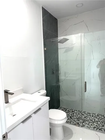 Full bathroom featuring vanity, a marble finish shower, and tile patterned floors