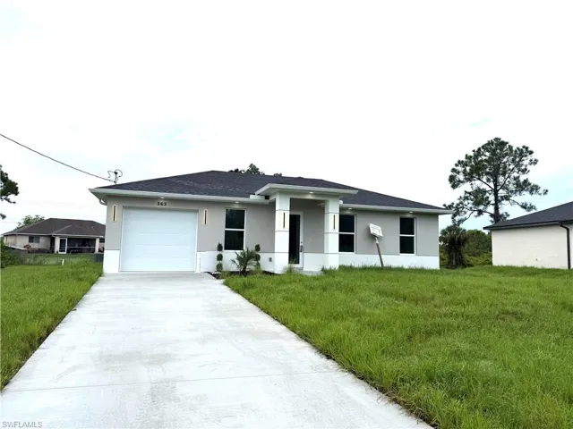 View of front facade with stucco siding, concrete driveway, a garage, and a front yard