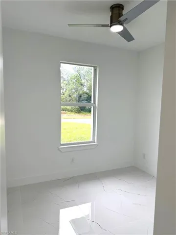 Unfurnished room featuring light marble finish flooring and a ceiling fan