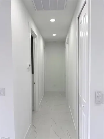 Hallway featuring light marble finish floors and recessed lighting