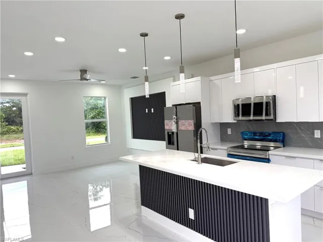 Kitchen featuring appliances with stainless steel finishes, decorative backsplash, light stone counters, white cabinetry, and recessed lighting