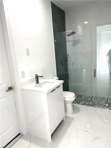 Full bath with vanity, a marble finish shower, and light marble finish floors