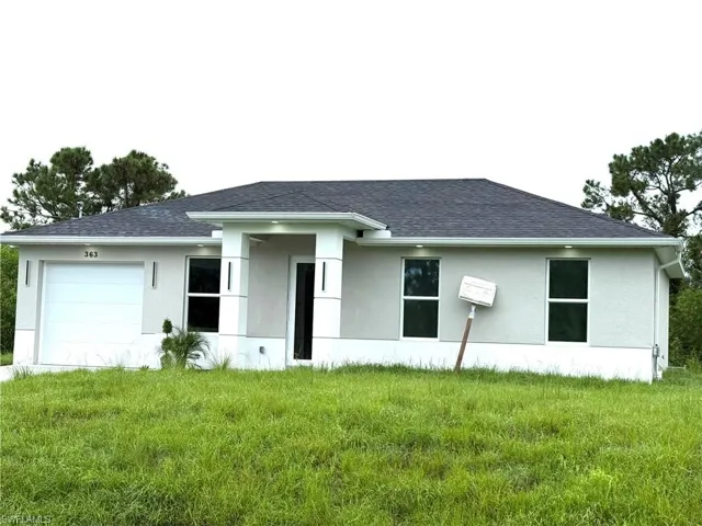 View of front of home featuring stucco siding, an attached garage, and a shingled roof
