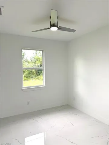 Spare room with ceiling fan and light marble finish flooring