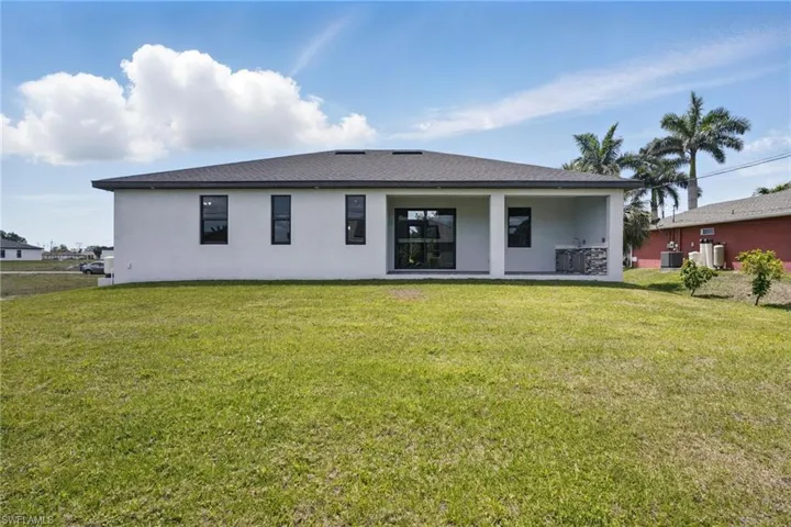 Rear view of property with a lawn, stucco siding, and a patio area