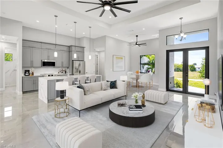 Living room featuring a high ceiling, a ceiling fan, recessed lighting, a chandelier, and a raised ceiling