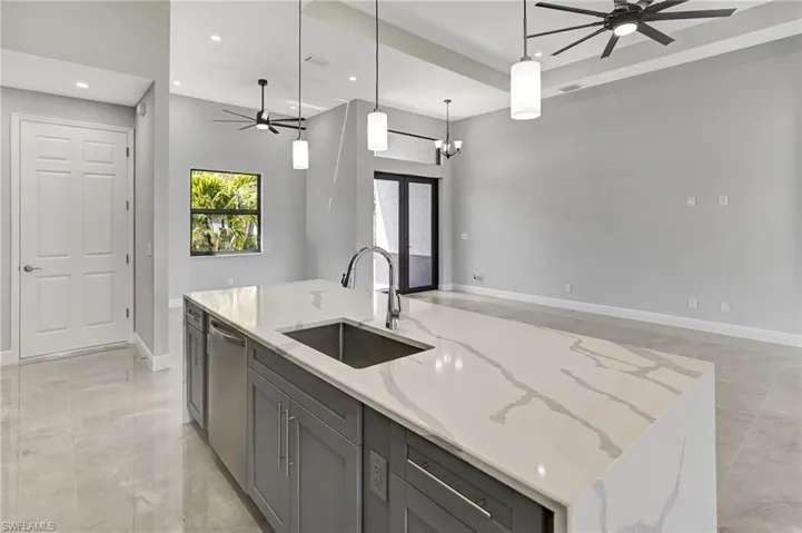 Kitchen featuring ceiling fan, recessed lighting, light stone countertops, a kitchen island with sink, and pendant lighting