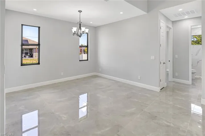 Spare room featuring light marble finish flooring, recessed lighting, and a chandelier