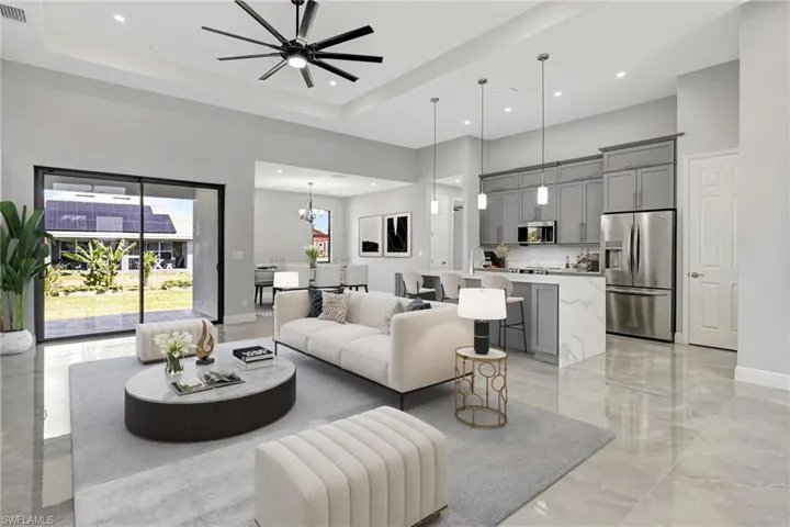 Living room with a chandelier, light marble finish flooring, a towering ceiling, ceiling fan, and a raised ceiling