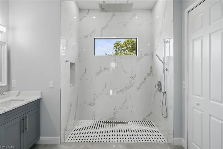 Bathroom featuring a marble finish shower and vanity