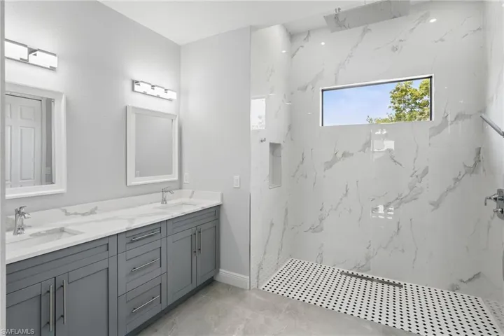 Full bathroom featuring a marble finish shower and double vanity