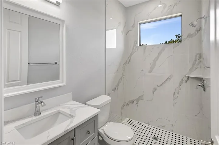 Full bathroom with a marble finish shower, vanity, and a textured wall