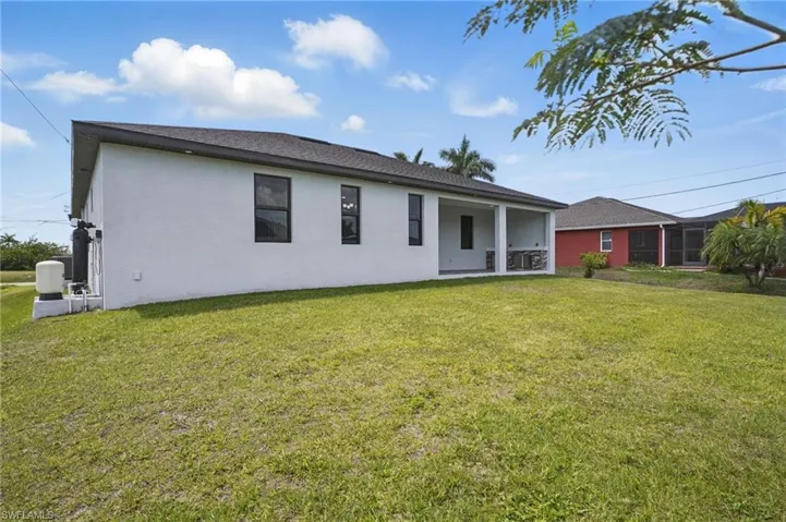 Rear view of property featuring a yard, a patio area, and stucco siding