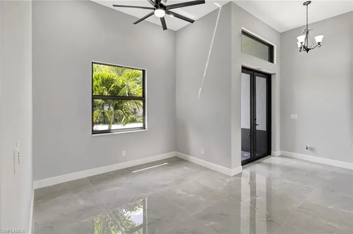 Spare room with a high ceiling, light marble finish floors, french doors, a chandelier, and ceiling fan