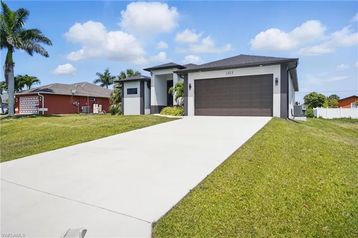 Prairie-style home with stucco siding, a front lawn, concrete driveway, and an attached garage