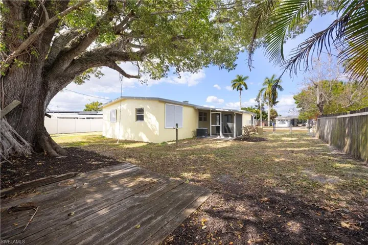 Rear view of house with a fenced backyard, a sunroom, and stucco siding