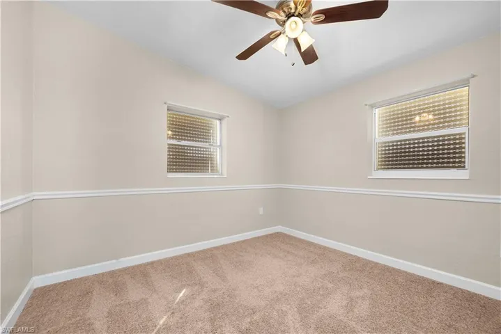 Empty room featuring light carpet, a ceiling fan, and lofted ceiling