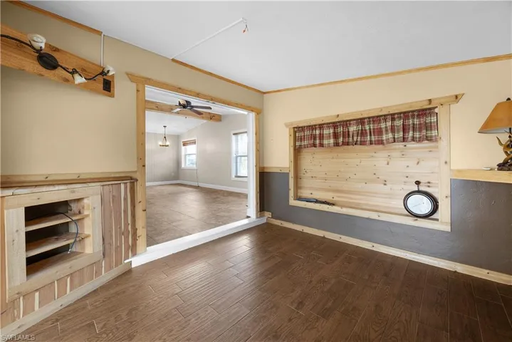 Unfurnished living room with wood finished floors, ornamental molding, and a ceiling fan