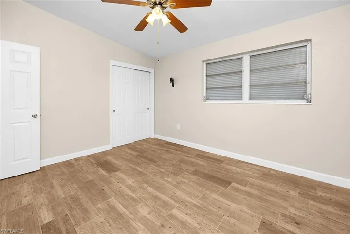 Unfurnished bedroom featuring a closet, lofted ceiling, light wood-style floors, and a ceiling fan