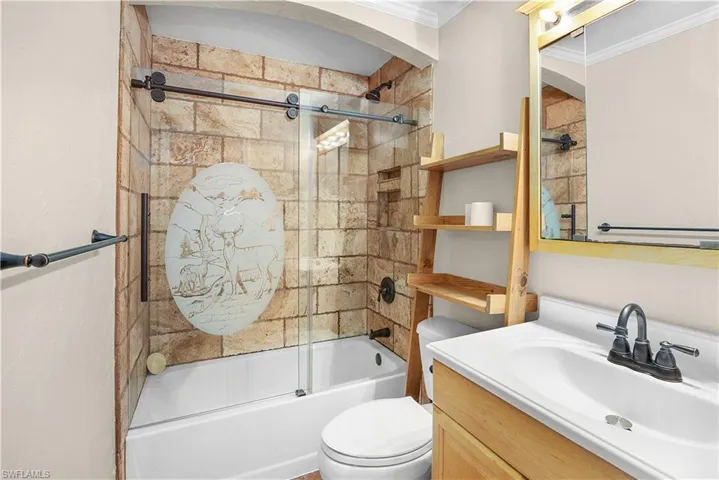 Full bath with shower / bath combination with glass door, vanity, and crown molding