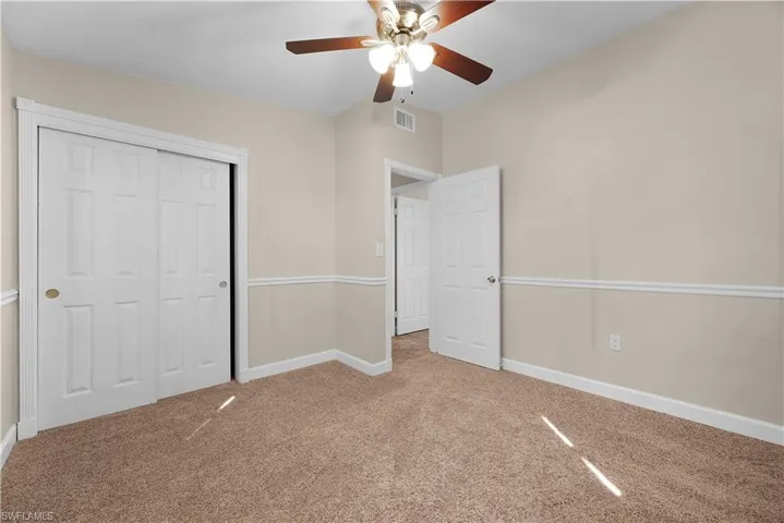 Unfurnished bedroom with carpet, a closet, and a ceiling fan