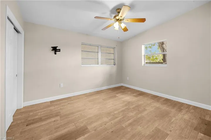 Unfurnished bedroom featuring a closet, light wood-type flooring, ceiling fan, and lofted ceiling