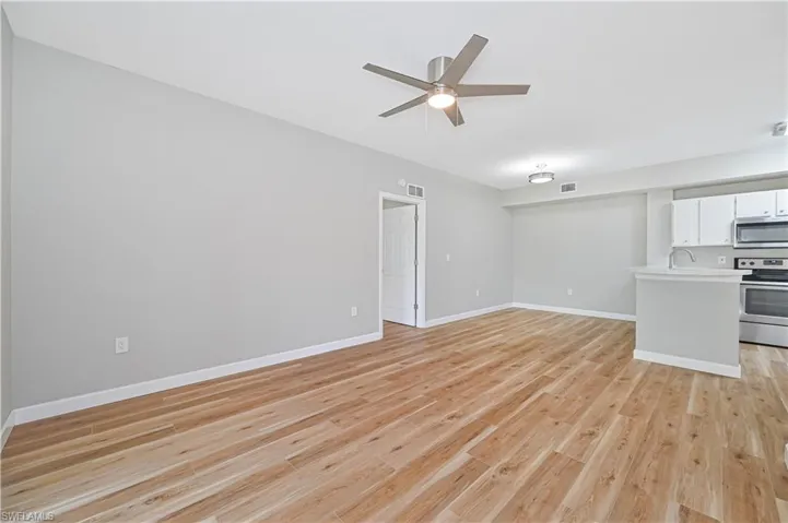 Unfurnished living room with sink, light hardwood / wood-style flooring, and ceiling fan