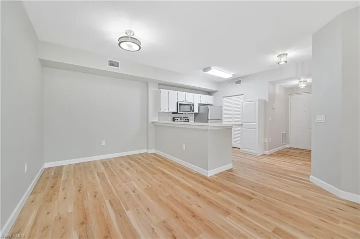 Kitchen featuring a breakfast bar, kitchen peninsula, white cabinets, light hardwood / wood-style floors, and appliances with stainless steel finishes