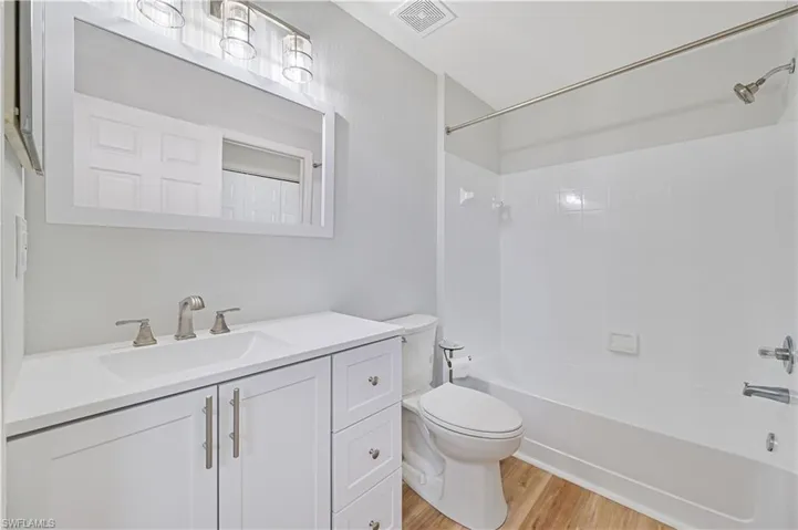 Full bathroom with vanity, shower / bath combination, hardwood / wood-style flooring, and toilet
