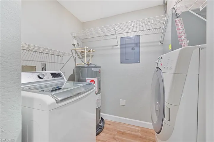 Laundry area featuring washer / dryer, light hardwood / wood-style flooring, electric water heater, and electric panel
