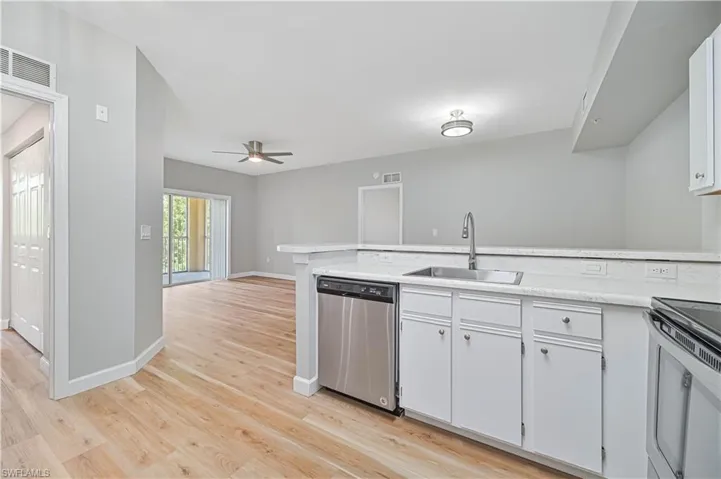 Kitchen with white cabinets, sink, stainless steel dishwasher, light wood-type flooring, and ceiling fan
