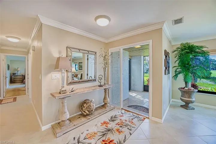 Foyer with crown molding and baseboards
