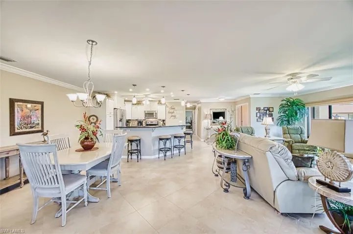 Dining area with ornamental molding, a ceiling fan, and suspended lighting