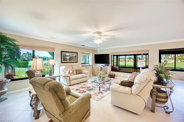 Living room with ceiling fan, healthy amount of natural light, light tile patterned flooring, and ornamental molding