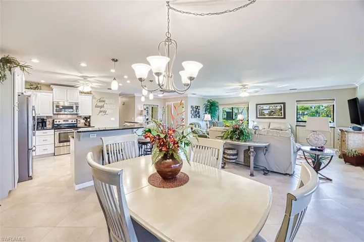 Dining area with ceiling fan, a chandelier, light tile patterned flooring, and crown molding