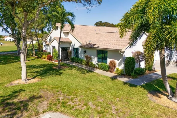 View of front of home featuring stucco siding, a front yard, and a shingled roof