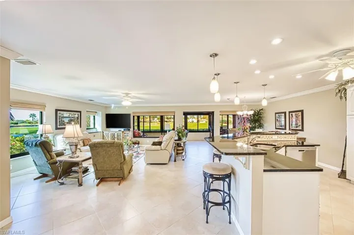 Kitchen featuring ceiling fan, a spacious island, a breakfast bar, ornamental molding, and hanging light fixtures