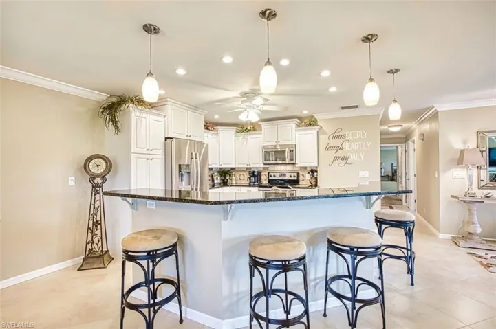 Kitchen featuring a breakfast bar area, dark stone countertops, tasteful backsplash, stainless steel appliances, and white cabinets